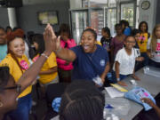 Ann-Audrey Ezi, left, gets a high-five from Amber Smith-St. Louis of the Norfolk Navy Shipyard after Ezi’s floating aluminum foil structure held the most marbles, 27, before sinking during a naval engineering session at FOCUS camp at George Mason University on June 28, 2017 in Fairfax, Virginia. The camp is designed to expose middle school-aged females of color to a variety of disciplines in science, technology, engineering and mathematics.