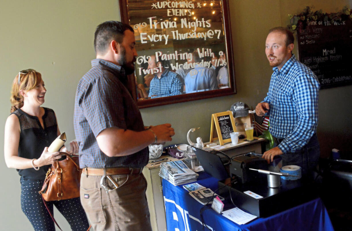 Zach Scott, right, greets Michael Krepsik and Ginger Randall in the Young Professionals in Energy gathering in Coraopolis. Zach Scott has been laid off from half a dozen oil and gas jobs. But he keeps coming back.