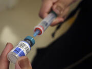 A vial containing the MMR vaccine is loaded into a syringe before being given to a baby at the Medical Arts Pediatric Med Group in Los Angeles.