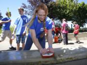 Volunteer Summer Fulcher, 16, of Vancouver, scrubs moss from the Vancouver Land Bridge Saturday as part of “The Amazing Race Youth Conference.”