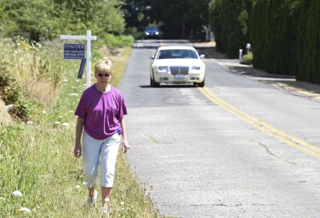 Vi Towne walks along Southeast Evergreen Highway near her home where there are no sidewalks for pedestrians. Towne usually drives a mile to the nearest area with a sidewalk for her walks. A collaboration between area residents and the city of Vancouver is working to provide a safe walking and cycling access along the former highway.