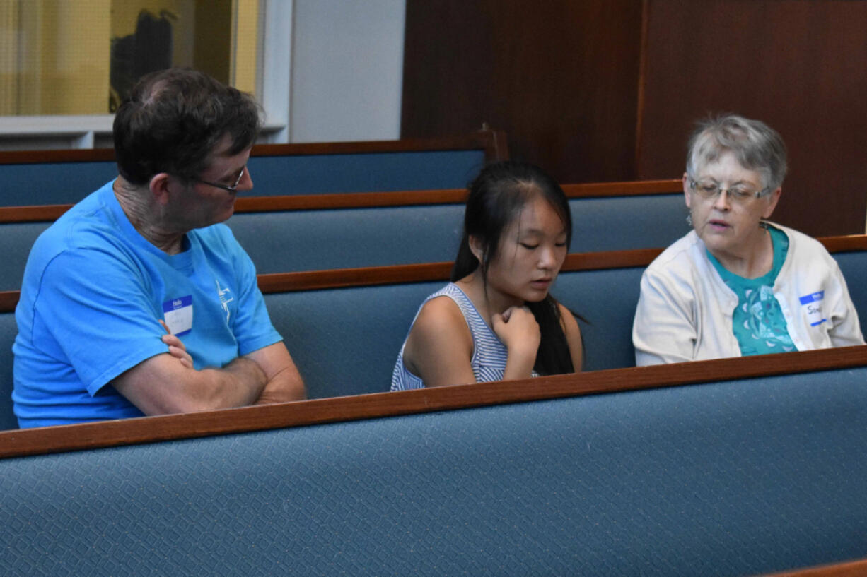 Salmon Creek: Thuy Nguyen, center, reads a book about Harriet Tubman with assistance from Greg Berry, left, and Sandie Hollister, volunteers with the Salmon Creek United Methodist Church’s Project Transformation summer reading program.