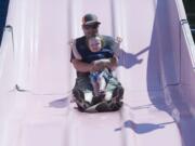 Gerard Nash and his son, Radley, 2 ride a slide at a carnival as part of Battle Ground Harvest Days on Saturday.