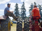 Bud Cronin, left, president of the Fort Vancouver Antique Equipment Association, chats with Lester Schurman, vice president of the association, atop antique tractors during the 23rd annual Rural Heritage Fair near Ridgefield Sunday. The event celebrates antique technology and techniques used on the farm and in daily life.