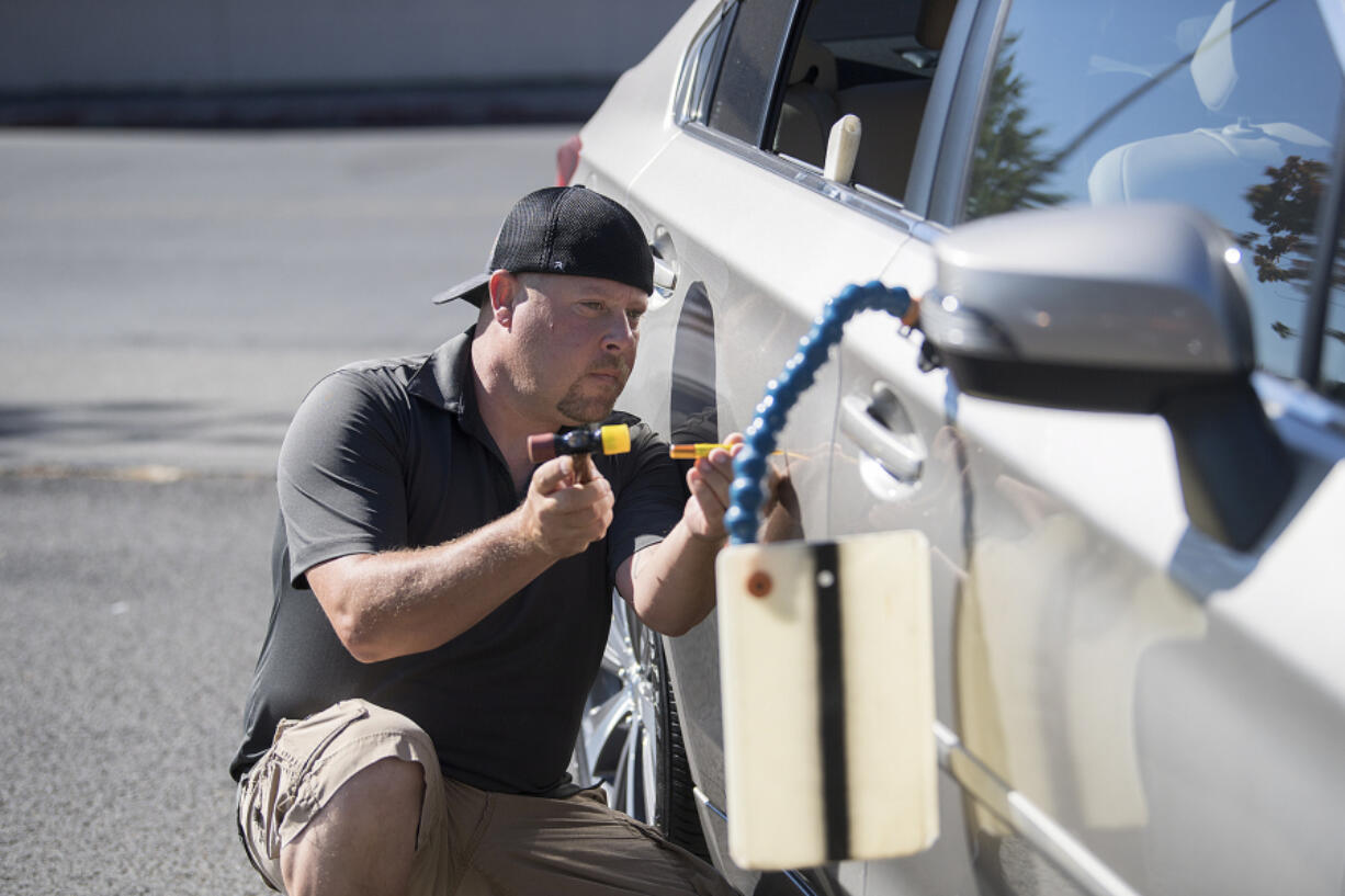 Clint Mather of Pacific Dent Removal fixes a dent on a vehicle from Dick Hannah Subaru. Mather and his partner have a mobile service and a loyal customer base.