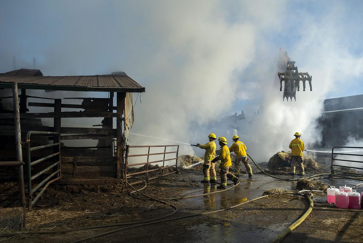 Smoke billows around firefighters as they work at the scene of a hay barn fire at a dairy farm in Ridgefield on Wednesday morning, July 19, 2017.