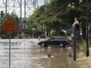 George Janzen of Vancouver, right, stays dry as he checks out the scene on Columbia Street after a water main break Thursday afternoon, July 20, 2017.