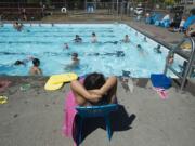 Zacil Castillo-Stengel, 5, of Camas, foreground, relaxes poolside while watching swimming lessons at the Crown Park pool. City officials are working on a master plan for upgrades to the pool, and one option replaces the pool with a new outdoor leisure pool, while the other replaces it with an interactive water feature with spray jets and bubblers.