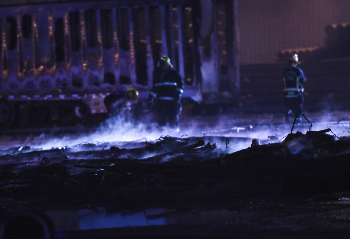 Camas-Washougal firefighters put out a hot spots after a Friday evening fire at Advanced Drainage Systems in Washougal. A damaged trailer, its sidewalls melted, is visible in the background.