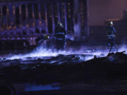 Camas-Washougal firefighters put out a hot spots after a Friday evening fire at Advanced Drainage Systems in Washougal. A damaged trailer, its sidewalls melted, is visible in the background.