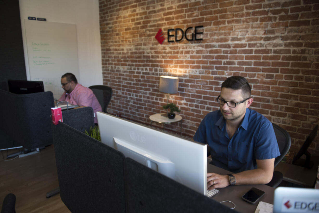 Josh McKinney, chief technology officer at Edge Networks, left, and President Mark Tishenko work at the downtown Vancouver office. The company has seen revenues rise 20 percent since offering an on-call cybersecurity service.