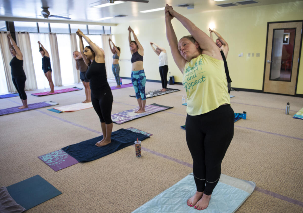 Kelli Rowe of Hazel Dell stretches into a pose during a class July 12 at Bikram Yoga Hazel Dell. After being injured in a car crash three years ago, Rowe found Bikram yoga as a way to heal. She has attended two classes a day since early May and intends on sticking with that schedule as long as she can.