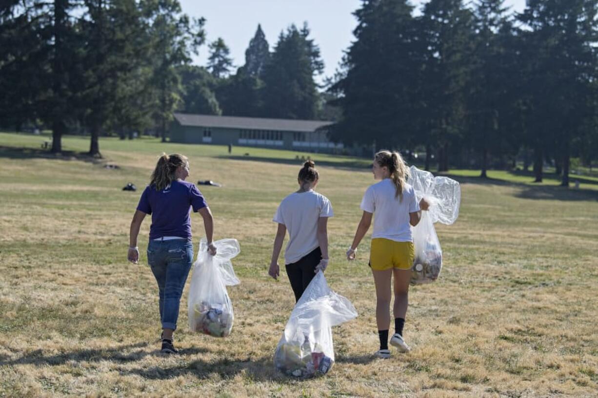 Woodland High School students Madysen Saucedo, 16, left, Joclyn Massey, 17, and Dana Glovick, 17, partake in the cleanup effort following Fourth of July festivities at Fort Vancouver National Historic Site on July 5. Organizers say this year’s event drew a large crowd.