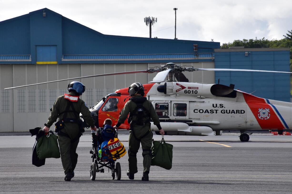 Coast Guard Petty Officer 1st Class Keola Marfil, honorary Petty Officer 3rd Class Andrew Bishop and Petty Officer 2nd Class Cody Dickey walk to an MH-60 Jayhawk helicopter during a search and rescue drill at Coast Guard Air Station Kodiak, Alaska, on July 8. Fulfilling Bishop's wish to be a rescue swimmer, they hoisted a hiker and simulated CPR while transporting him to the air station. (U.S. Coast Guard photo by Lt. Cmdr.