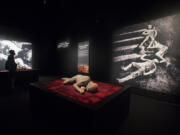 A visitor, left, reads a panel in the room where casts of six victims of Mount Vesuvius are on display. The image to the right shows the casts of three people who died in what is called the Alley of the Skeletons.