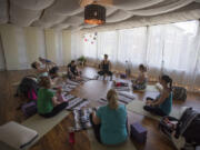 Daniele Strawmyre, top center, leads women through her Mommy and Me Yoga class on June 30 at Vancouver Wellness Studio. The class is open to women at least four weeks postpartum and their babies.