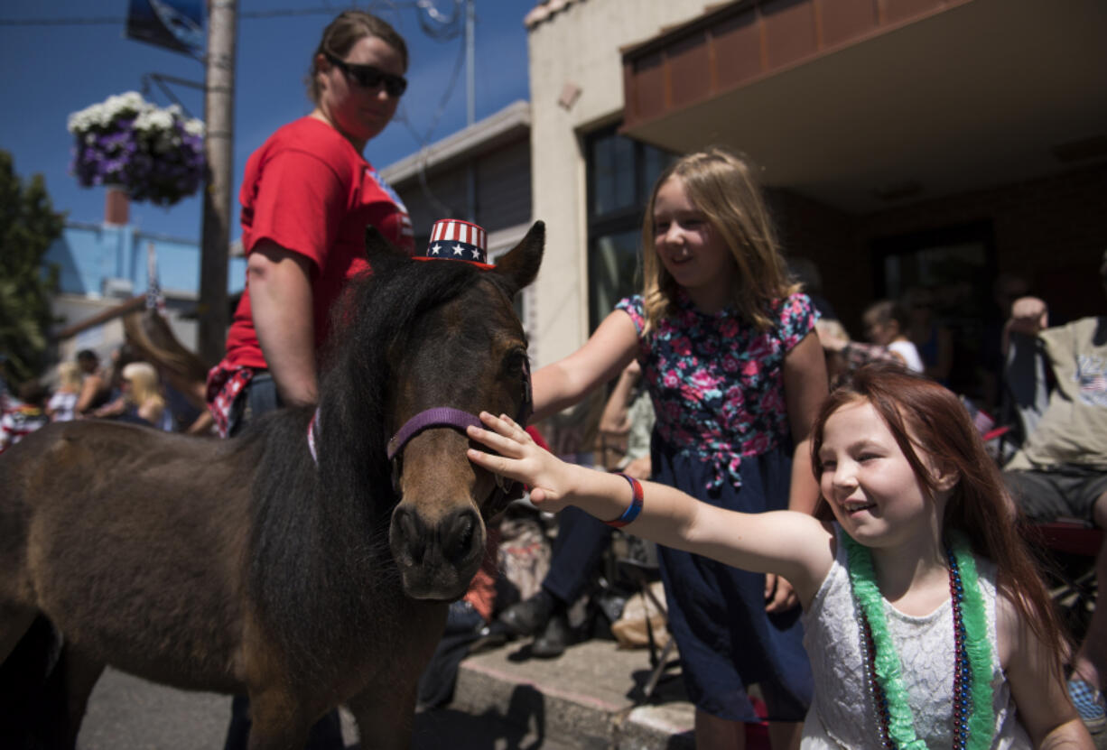 Baylee Long, 9, center, and Maddy Sanford, 8, right, pet a miniature horse during the Wild, Wild, West 4th of July parade in downtown Ridgefield on Tuesday afternoon.