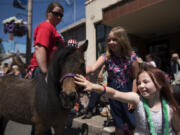 Baylee Long, 9, center, and Maddy Sanford, 8, right, pet a miniature horse during the Wild, Wild, West 4th of July parade in downtown Ridgefield on Tuesday afternoon.