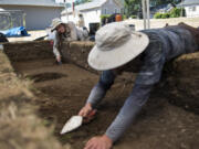 Co-field director Katie Wynia of Portland, from left, and Portland State University graduate Jesse Nelson of Portland trowel a dig site Friday during the annual archaeological summer field school on the south side of Vancouver Barracks in the Fort Vancouver National Historic Site.