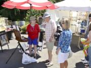 Artist Lila Martin, left, chats with Tom and Judy Barker during the Red Wine, Blues and Art in the Vineyard Festival at Confluence Vineyards and Winery in Ridgefield on Sunday afternoon. The winery has held a wine and blues event, and a separate art show, each July for the past few years and combined them for this year.