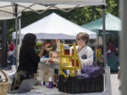 Danielle Davis, left, of Give Us A Buzz, talks with customer Rachel Belveal, who works at the Clark County Treasurer’s Office, at the Franklin Street Farmers Market on Wednesday afternoon. The market debuted Wednesday and will take place every Wednesday through August.