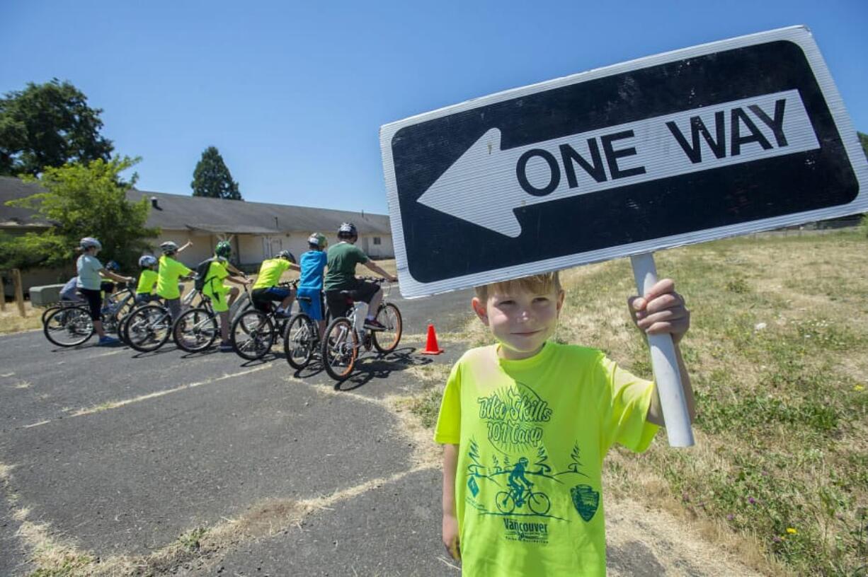 Julian Charbonneau, 8, helps with the signage Tuesday as cyclists prepare to take off from the starting line during Bike Skills 101 Camp at Fort Vancouver National Historic Site.