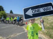 Julian Charbonneau, 8, helps with the signage Tuesday as cyclists prepare to take off from the starting line during Bike Skills 101 Camp at Fort Vancouver National Historic Site.