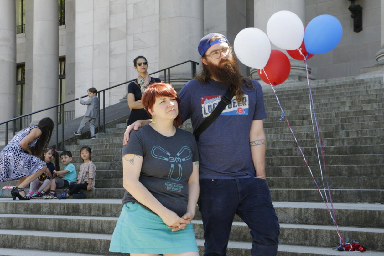 Sara and Nate Reilly, owners of Three Magnets Brewing Company and Darby's Cafe in Olympia, listen to speeches in support of a paid family leave measure, on Wednesday, July 5, 2017 in Olympia, Wash. After it was signed into law by Gov. Jay Inslee, Washington state became the fifth state to guarantee paid family leave.