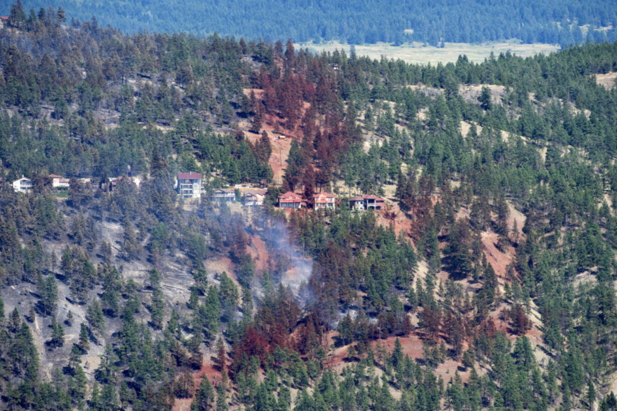 Smoke and fire retardant are seen along a neighborhood in Lake Country, British Columbia, Sunday, July 16, 2017.