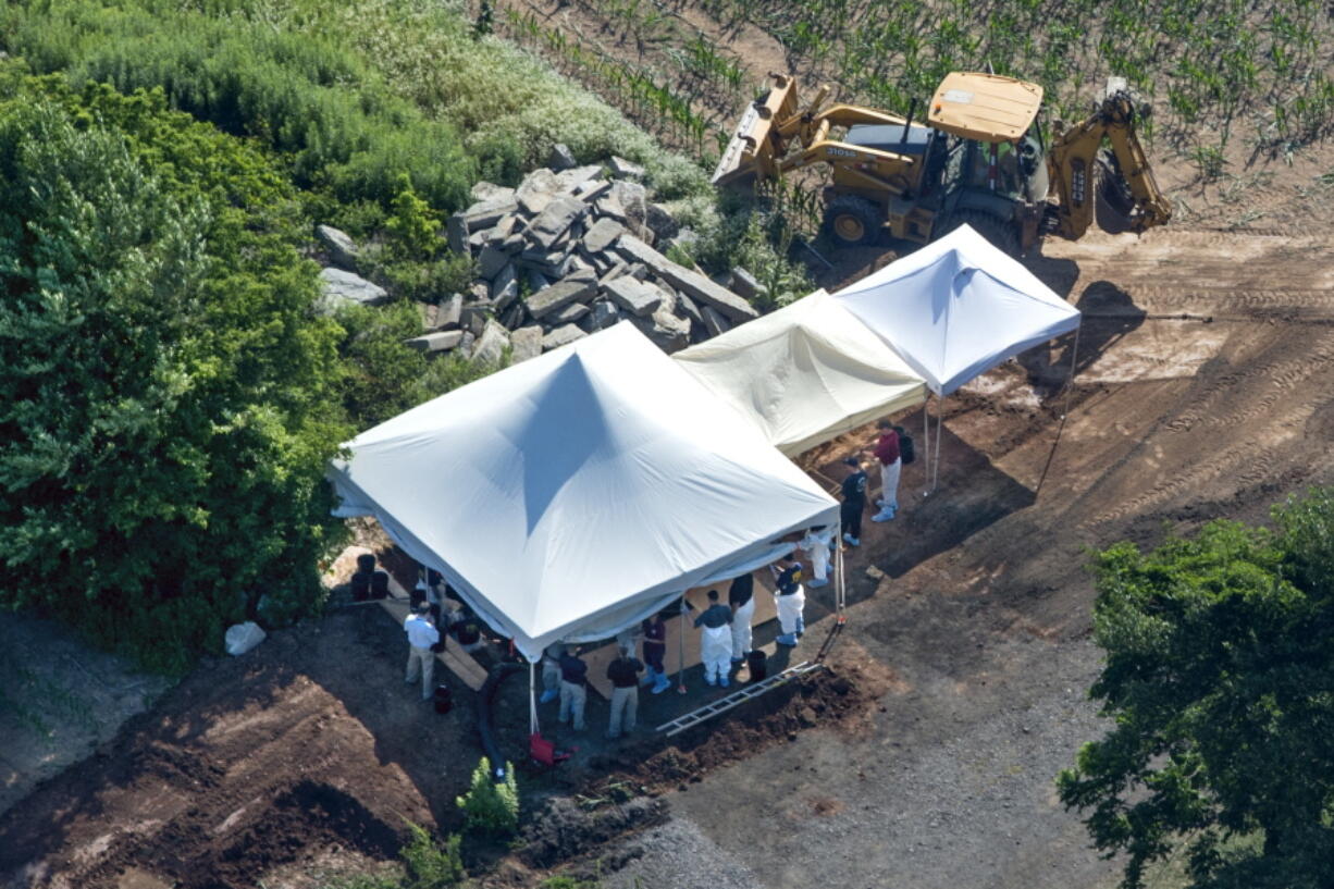 Investigators gather under tents as they search a property Wednesday in Solebury, Pa., for four missing young Pennsylvania men feared to be the victims of foul play.