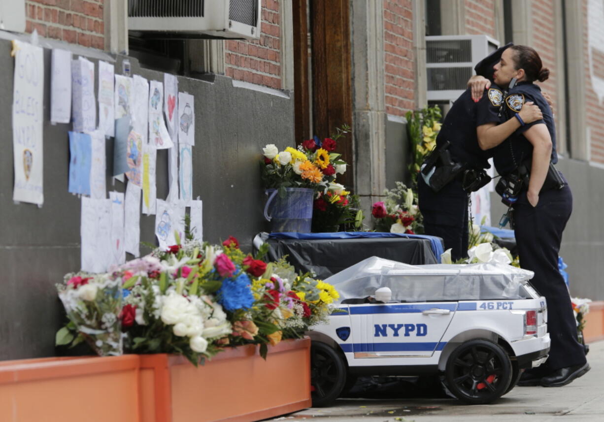 Police officers hug in front of the 46th Precinct in the Bronx borough of New York, Thursday, July 6, 2017. Police officer Miosotis Familia, who worked out of the 46th Precinct, was shot to death the day before, ambushed inside her command post RV by an ex-convict who once ranted online about his treatment in prison and about police getting away with killing people, authorities said. He was later killed after pulling a gun on police.