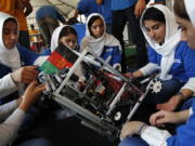 Lida Azizi, right, and other members of the Afghanistan team make a repair to their robot after their first round competing in the FIRST Global Robotics Challenge, Monday in Washington. The challenge is an international robotics event with teams from over 100 countries.