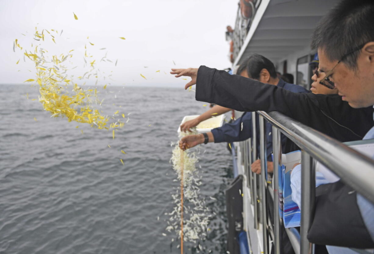 Liu Xia, in black, wife of imprisoned Chinese Nobel laureate Liu Xiaobo, throws flower petals as Liu’s ashes are buried at sea off the coast of Dalian on Saturday in northeastern China’s Liaoning Province.