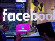 Conference workers speak in April in front of a demo booth at Facebook’s annual F8 developer conference in San Jose, Calif. Facebook blamed a technical glitch on Wednesday for knocking several Catholic-focused Facebook pages with millions of followers offline for more than a day.