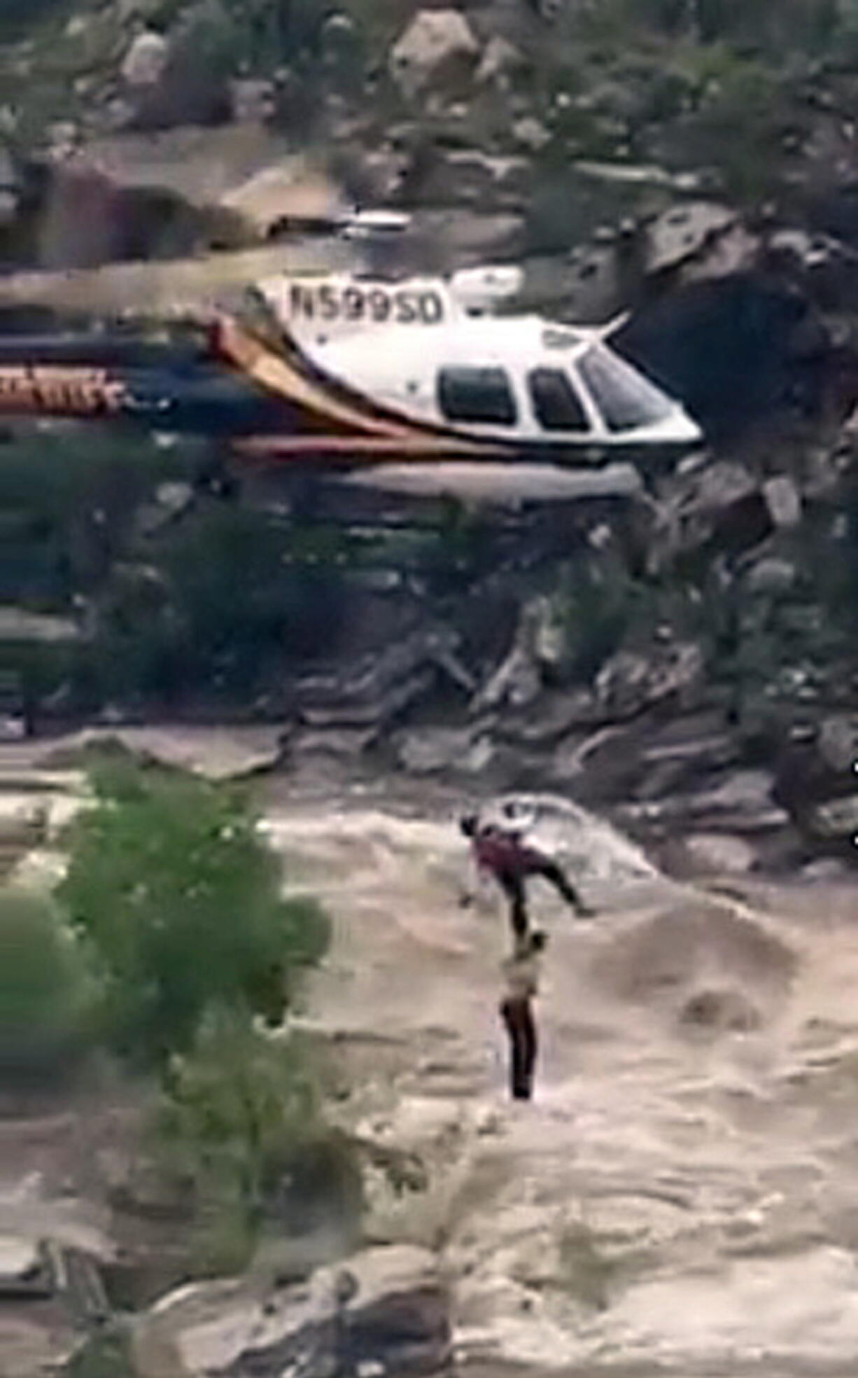 A stranded hiker is rescued Sunday from torrential flash flood waters near Tucson, Ariz.