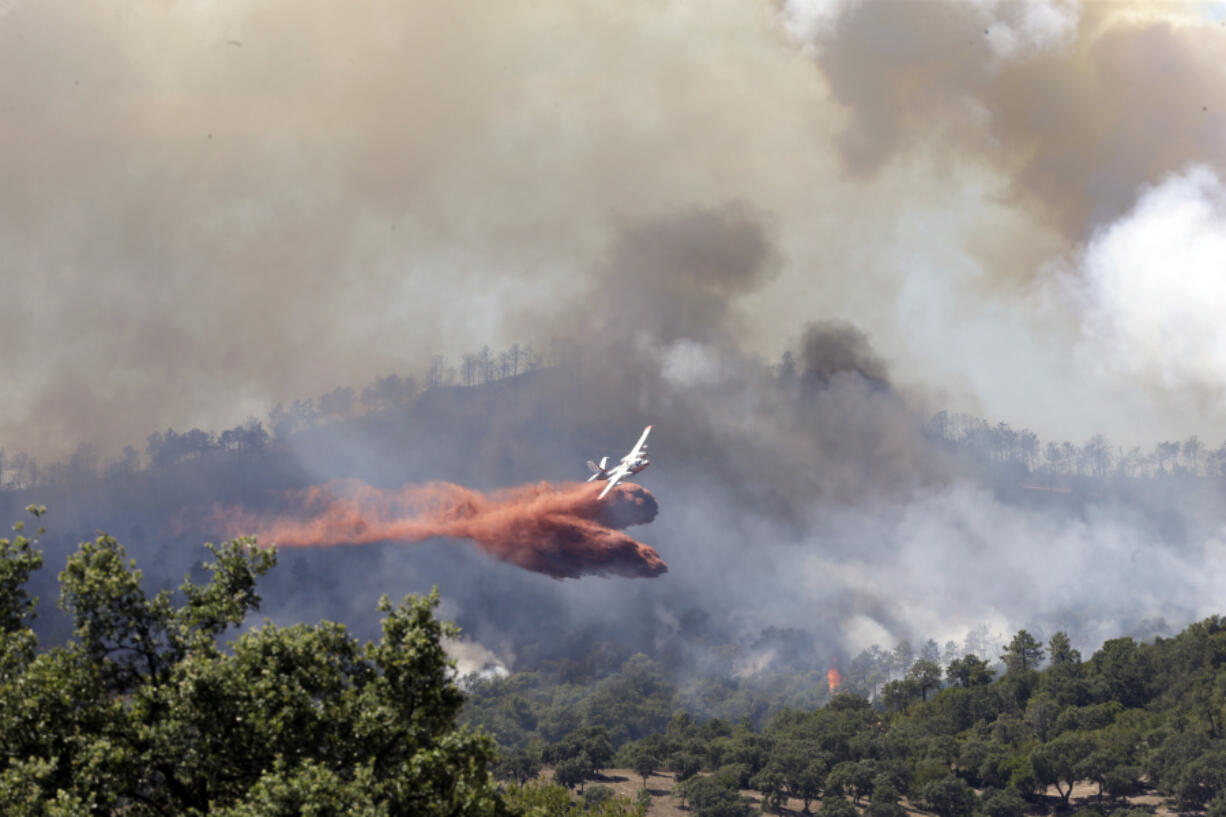 A firefighting plane drops fire retardant over a forest in the outskirts of La Londe-les-Maures on the French Riviera, Wednesday, July 26, 2017. Authorities ordered the evacuation of 10,000 people as fires hopscotched around the Riviera for a third day Wednesday, tearing through the forest of La Londe-les-Maures.