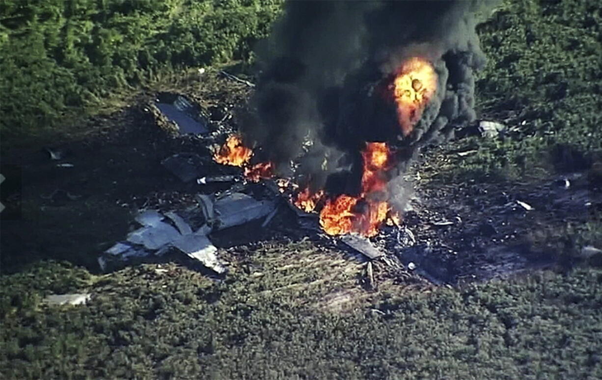 Smoke and flames rise from a military plane that crashed in a farm field, in Itta Bena, Miss., killing several.