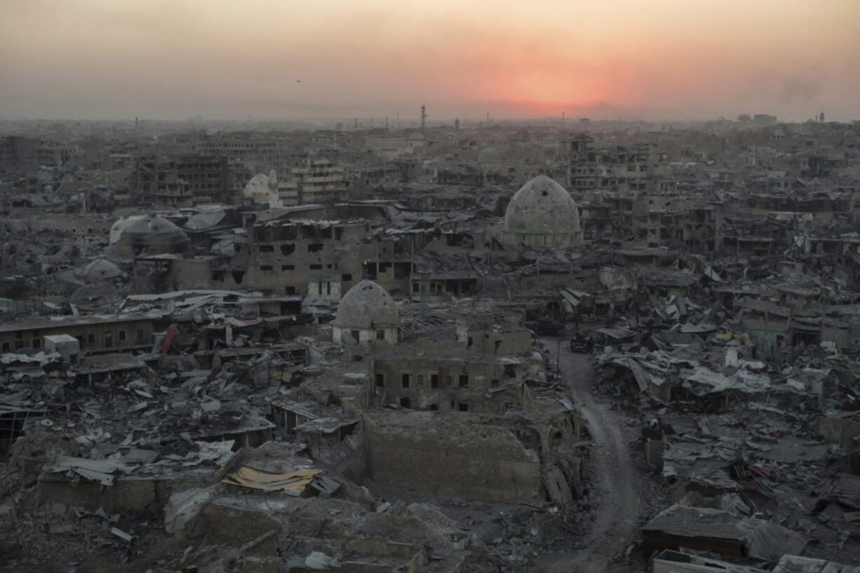 The sun sets behind destroyed buildings Tuesday in western Mosul, Iraq.