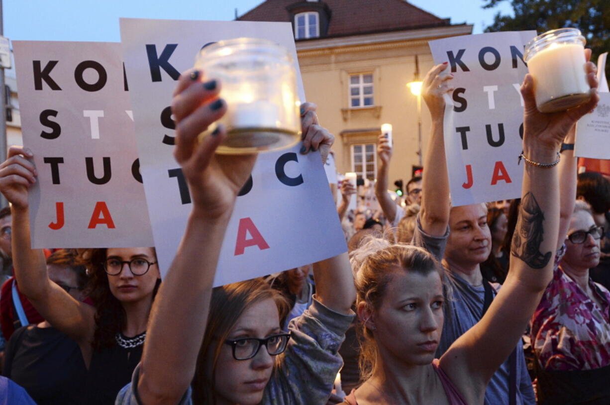 Anti-government protesters raise candles and placards reading “Constitution”, as they gather Saturday in front of the Supreme Court in Warsaw, Poland.