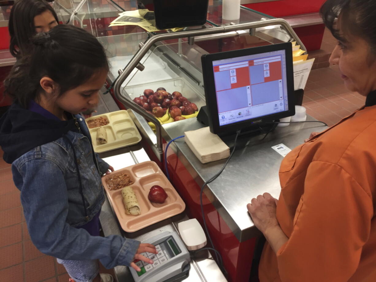 Third grader Elliana Vigil punches in his student identification meal to pay for a meal at Gonzales Community School in Santa Fe, N.M. All students are offered the same lunch at Gonzales and other Santa Fe public schools to avoid any chance of embarrassing students whose parents may have fallen behind on meal payments. New Mexico in April became the first state to outlaw the shaming of children for any unpaid meals.