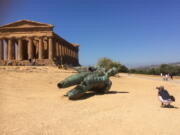 This April 14, 2017 photo shows tourist Matthew Kirkland taking a photo of a bronze statue at the Valley of the Temples in Agrigento, Sicily, Italy. The seven Greek temples date to ancient times and have been declared a UNESCO World Heritage site.