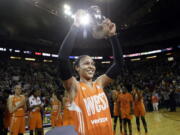 Minnesota Lynx’s Maya Moore, of the Western Conference, holds up a trophy after being named most valuable player as teammates cheer behind after the WNBA All-Star basketball game Saturday, July 22, 2017, in Seattle.(AP Photo/Elaine Thompson)