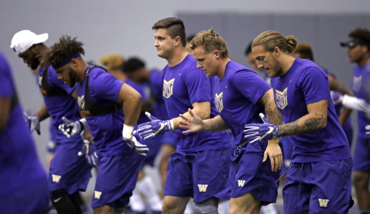 Washington defensive players run through a drill at the team’s first official NCAA college football practice of the year Monday, July 31, 2017, in Seattle.