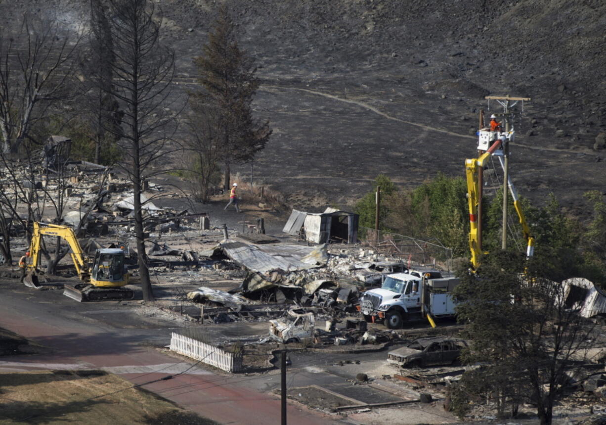 B.C. Hydro workers repair power lines among the remains of mobile homes destroyed by wildfire in Boston Flats near Ashcroft, British Columbia, Sunday, July 9, 2017. Wildfires barreled across the baking landscape of the western U.S. and Canada, destroying a smattering of homes and forcing thousands to flee.