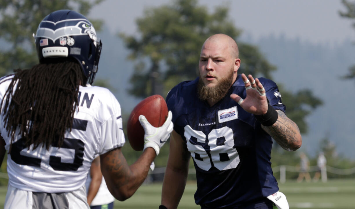 Seattle Seahawks' Justin Britt (68) greets Richard Sherman during an NFL football training camp Friday, Aug. 4, 2017, in Renton, Wash.