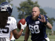 Seattle Seahawks' Justin Britt (68) greets Richard Sherman during an NFL football training camp Friday, Aug. 4, 2017, in Renton, Wash.