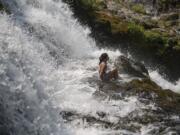 Angela Trinh, 14, of Portland takes a seat while cooling off in Dougan Falls with other visitors escaping the heat northeast of Washougal in Skamania County on Wednesday afternoon, Aug. 2, 2017. Trinh said this was her first time visiting the scenic spot, which she found out about while searching online. "It's really fun. It's super beautiful," she said. Residents flocked to local swimming holes as temperatures were forecast to approach 100 degrees Wednesday.