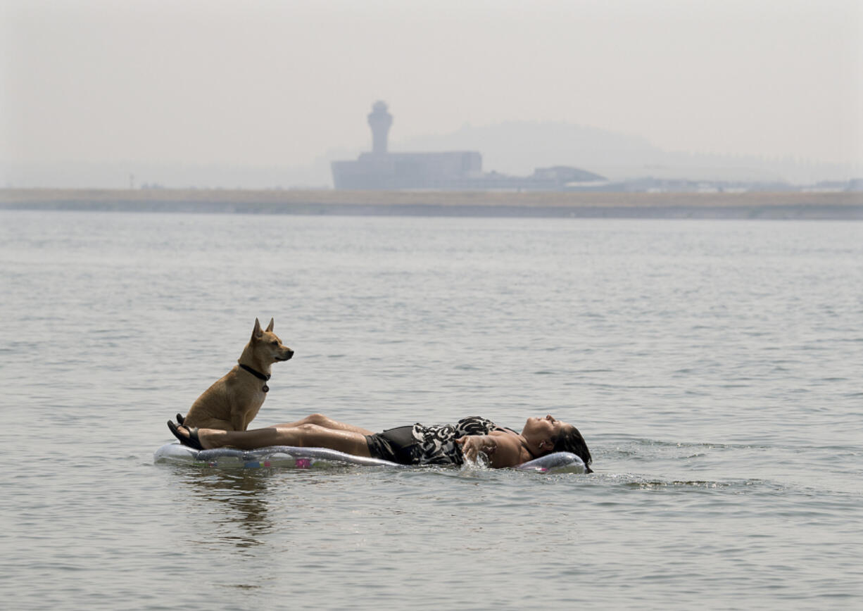 Marina Vanegas of Vancouver floats in the Columbia River at Wintler Park with her dog, Onyx, on Thursday afternoon with Portland International Airport in the background. The day’s high temperature of 105 degrees set a record for Aug. 3 in Vancouver. “This is like heaven for me,” the former Arizona resident said.