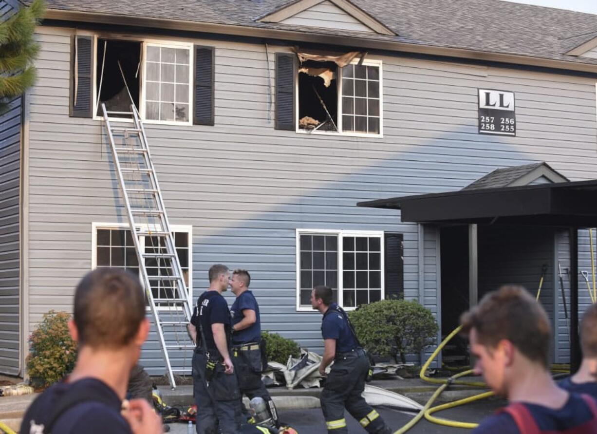 Firefighters clean up after a fire at Madison Park Apartments in Vancouver damaged multiple apartments and several nearby homes Thursday.