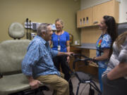 Navy veteran Ron Holcomb tries out the new exam room seat Wednesday as he chats with nurse case manager Sarah Olson, nurse Stefanie Broders and his daughter, Gina Green, during a tour of the new primary care clinic on the Vancouver VA campus.